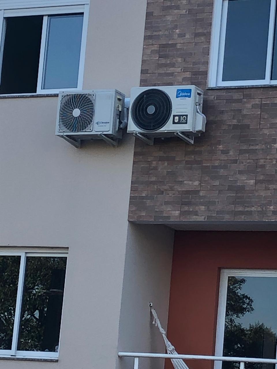 duas unidades condensadoras de ar-condicionado Midea instaladas em suportes metálicos na fachada de um prédio 